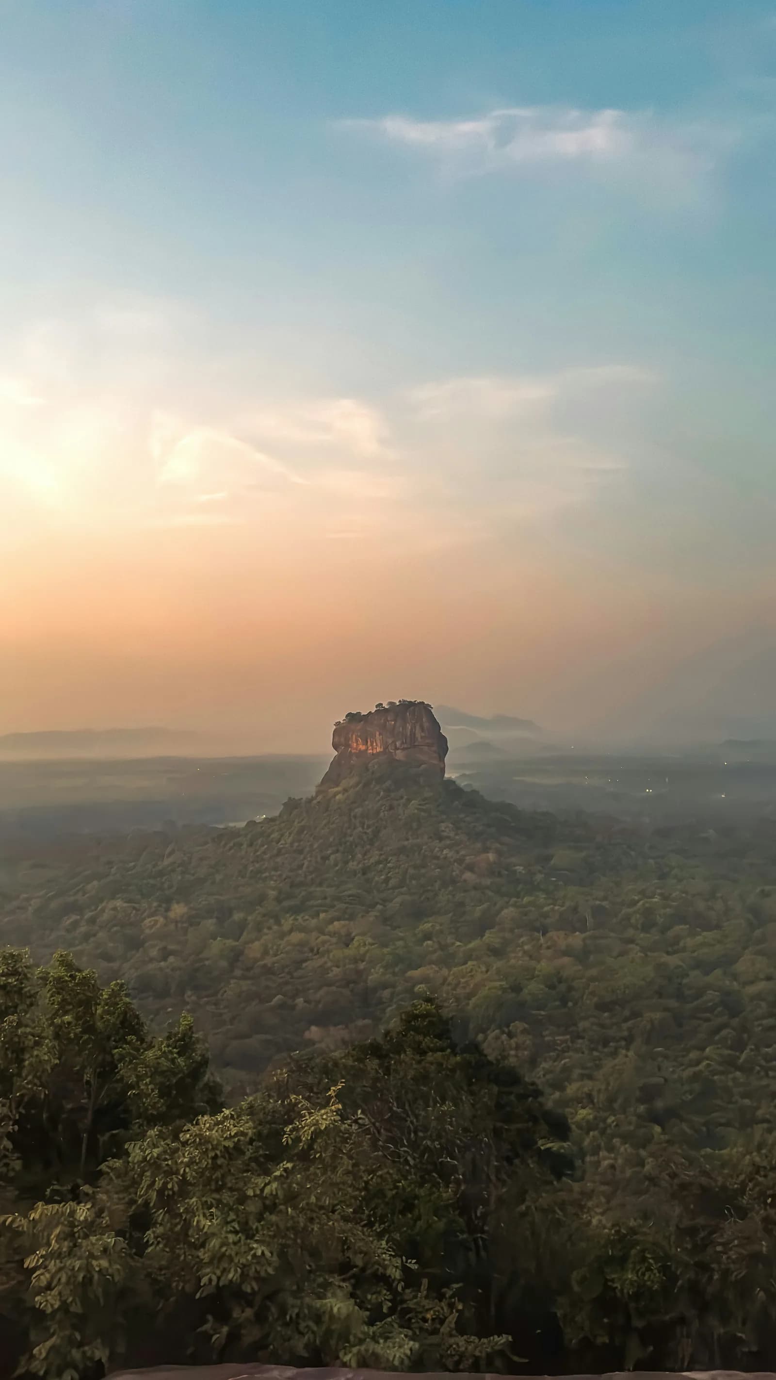 Traveler gazing across the lush green Sri Lankan canopy towards Sigiriya Lion Rock.